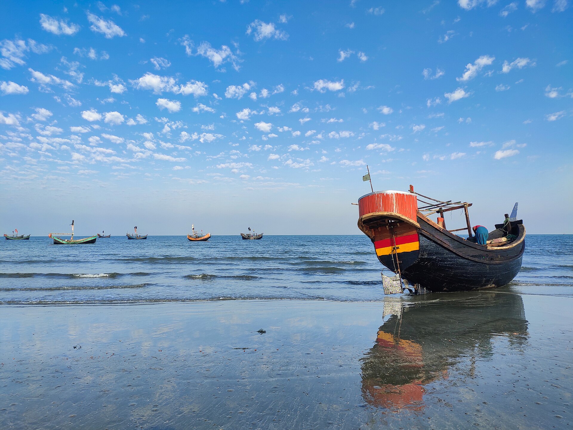 A fishing boat resting on a wet beach at Saint Martin's Island