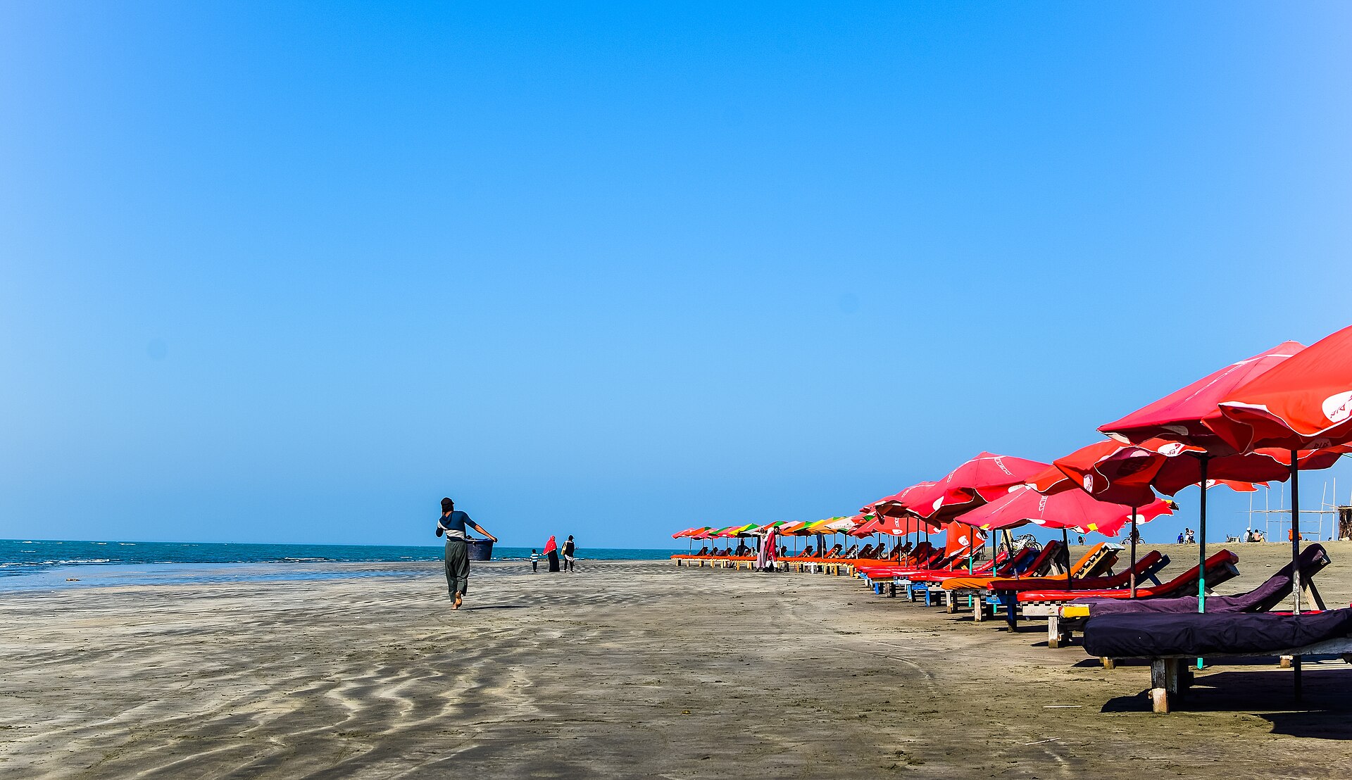 Beach chairs and umbrellas along a wide, flat beach at Cox's Bazar